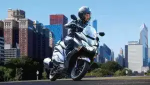 Suzuki Burgman Street 125Ex: Skuter Stylish Dan Performa Andal Untuk Penggemar Otomotif Pengendara Menggunakan Suzuki Burgman Street 125Ex Di Jalan Perkotaan Dengan Latar Belakang Gedung Kota
